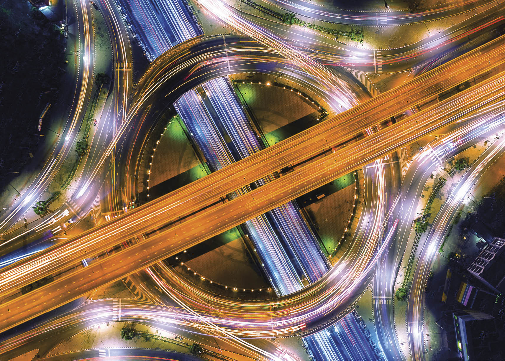 Aerial view of traffic in roundabout and highway at night.
