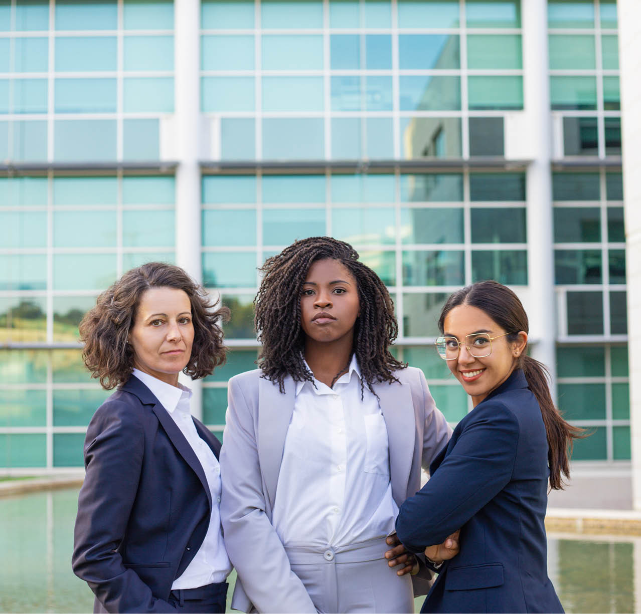 Team portrait of three successful businesswomen. Women wearing office suits, standing together outside and looking at camera. Female business team concept