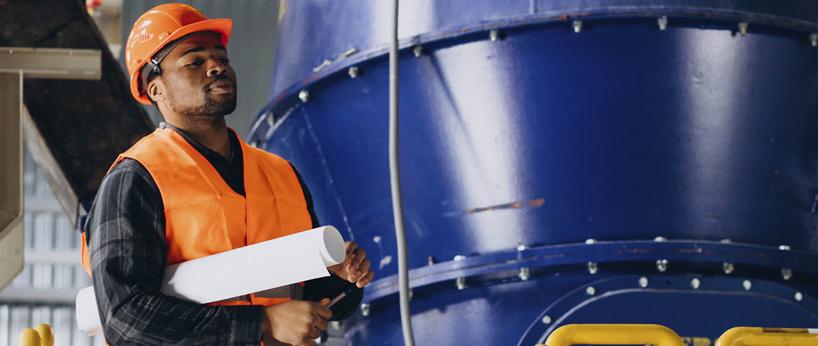African american worker standing in uniform wearing a safety hat in a factory