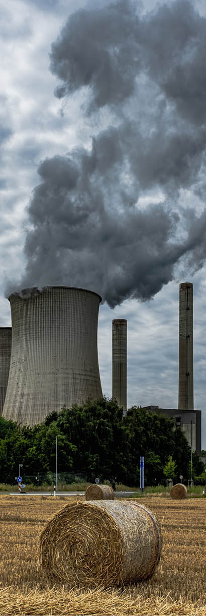 A vertical shot of rising smoke making the air polluted and hayricks in the field