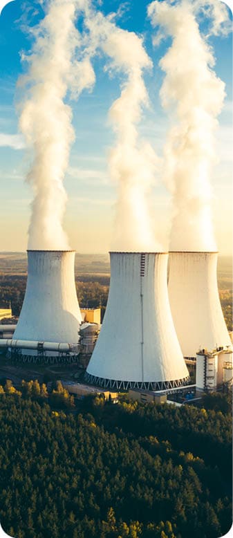 A Power plant with white smoke over it's chimneys