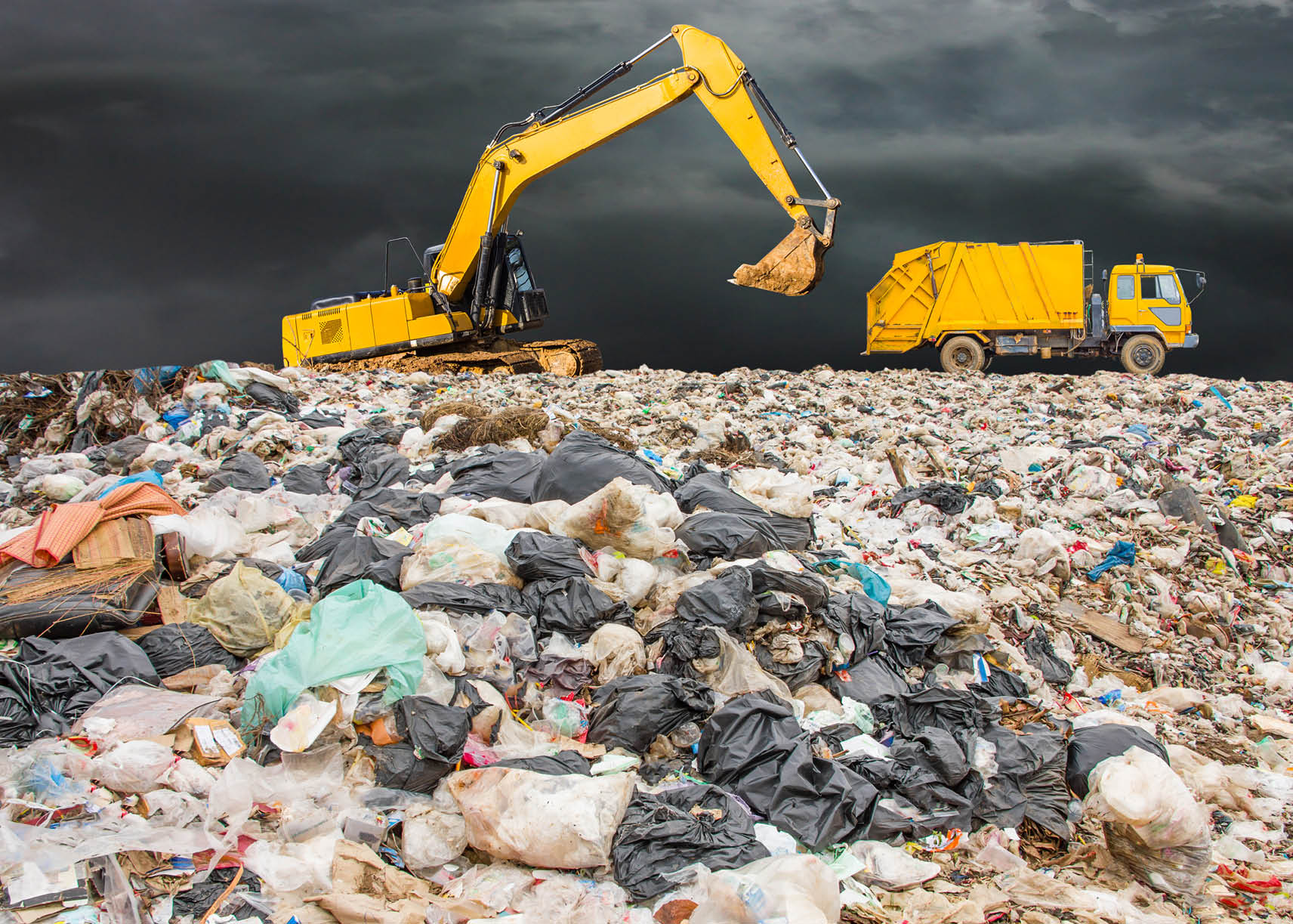 garbage dump pile in trash dump or landfill,backhoe and truck is dumping the gabage from municipal,garbage dump whit old garbage truck and dark clouds or rain clouds