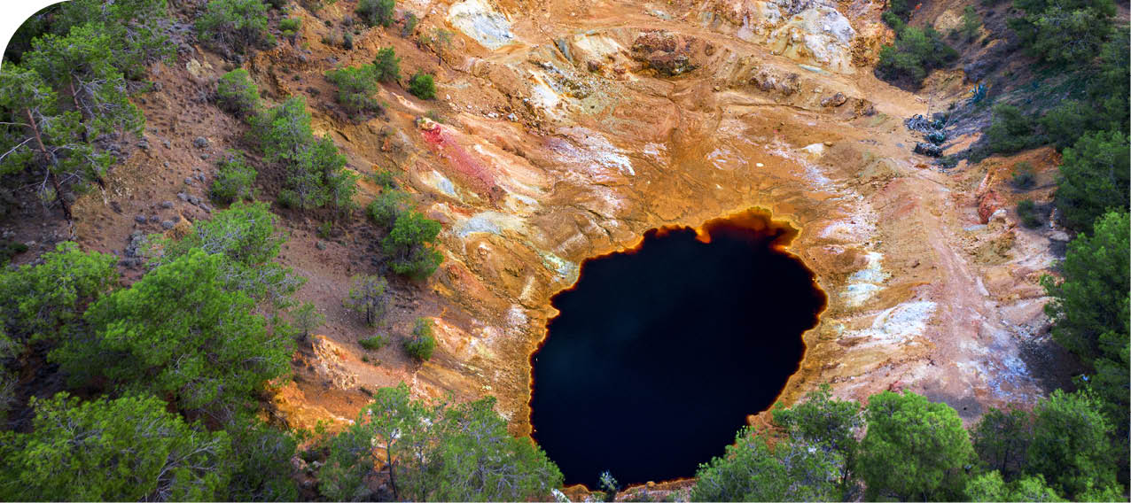 Abandoned open pit mine near Mathiatis, Cyprus. Aerial view on acidic red lake and colourful mine tailings left after pyrite ore extraction